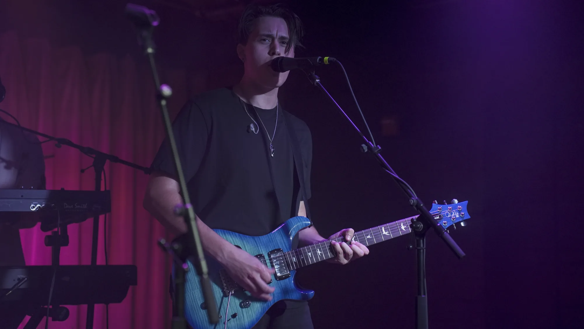 Guitarist performing under violet stage lighting